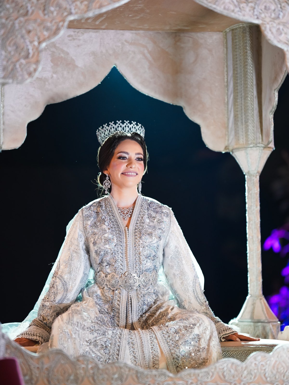 Mariée marocaine en caftan argenté sous une arche traditionnelle